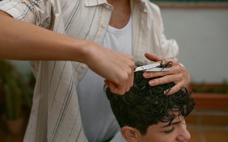 Image of a person with curly hair getting a haircut