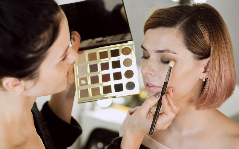 A stock photo of a makeup artist demonstrating eye makeup on a model.