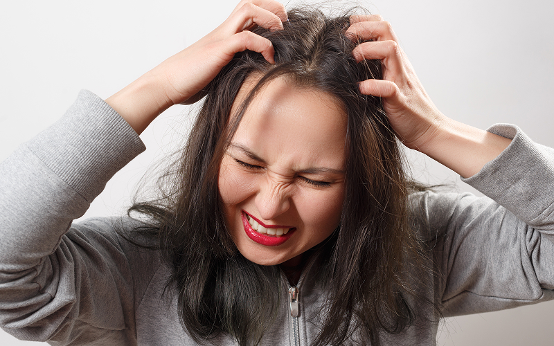 A stock photo of a model having scalp irritation.