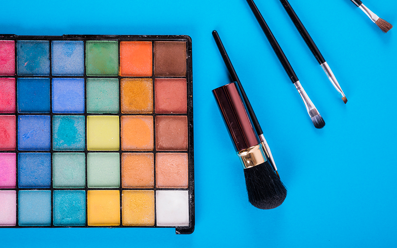 A stock photo of makeup brushes arranged beside an open palette.
