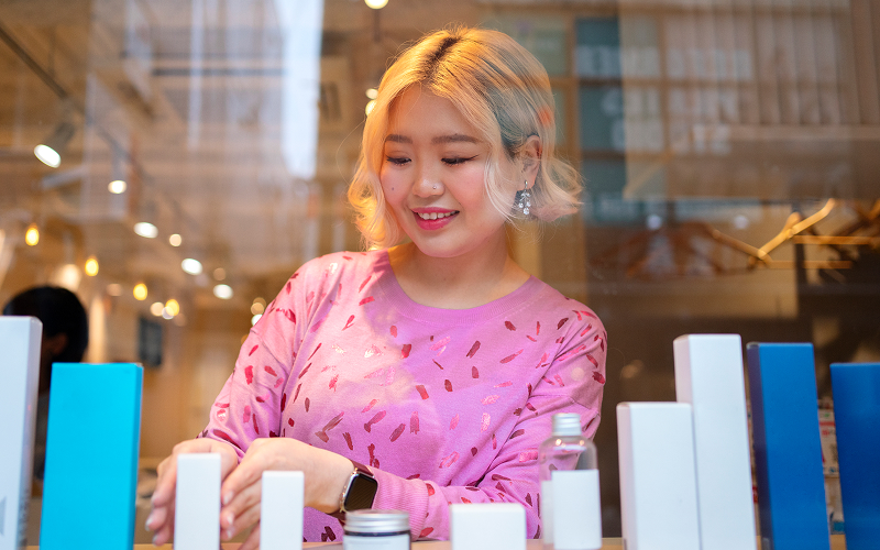 A woman inspecting a Korean skincare product closely under good lighting.