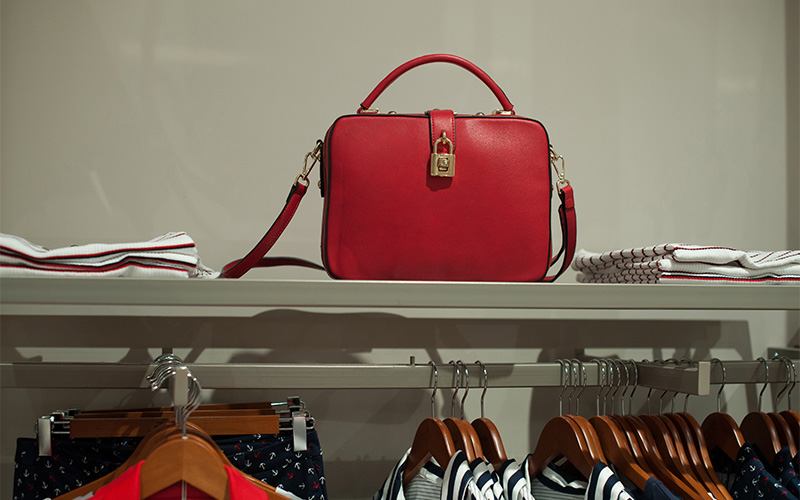 classic structured handbag on shelf beside trendier bags