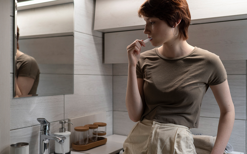 tired person at bathroom sink staring at skincare bottles