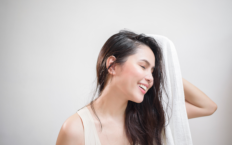 A woman drying her hair with a towel