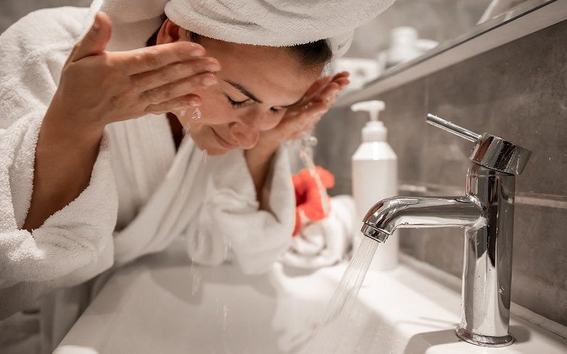 a woman washing her face with a cleanser